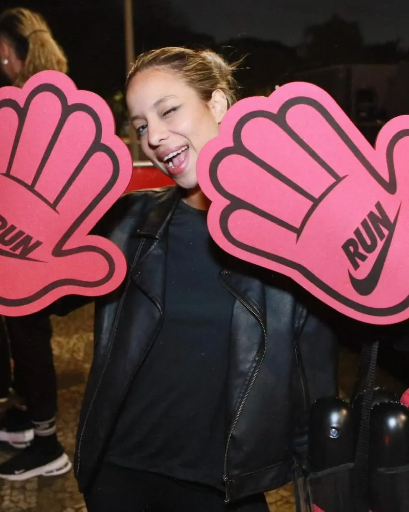 Participante de evento Nike Run segurando duas mãos gigantes de torcida em EVA rosa